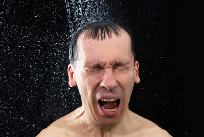 Man in shock having a cold shower after hot water ran out